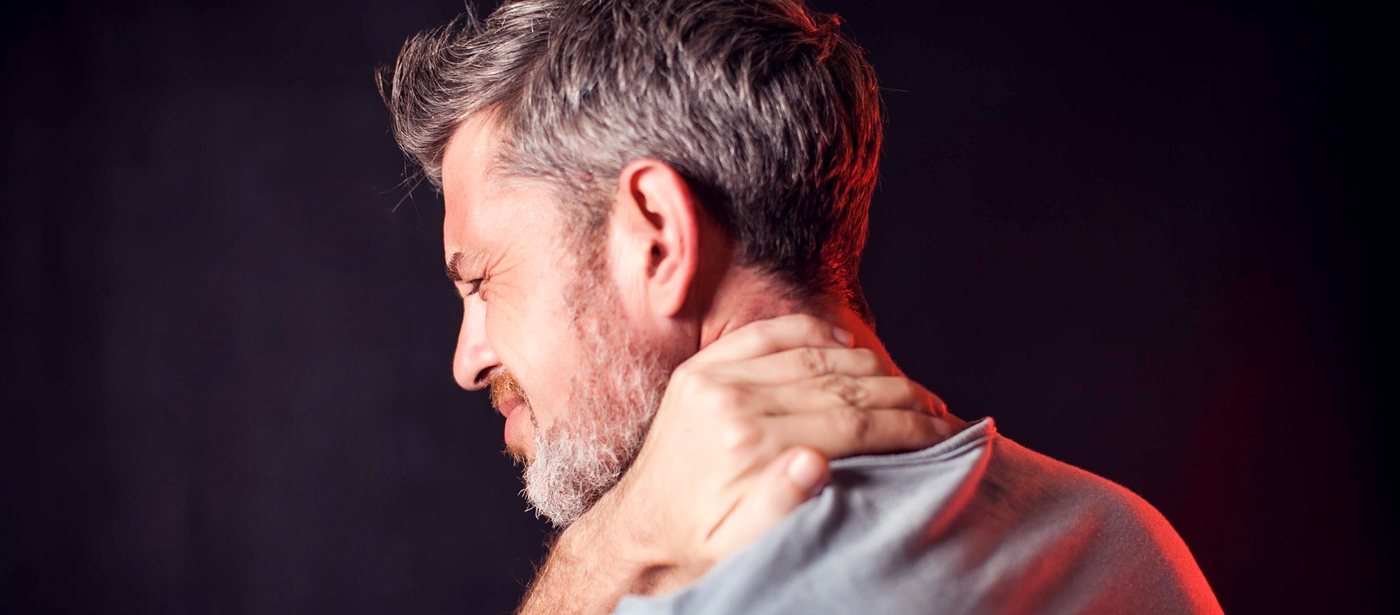 Man gripping the side of his neck in pain, neck muscle pain treated with neuromuscular therapy in Greenville SC